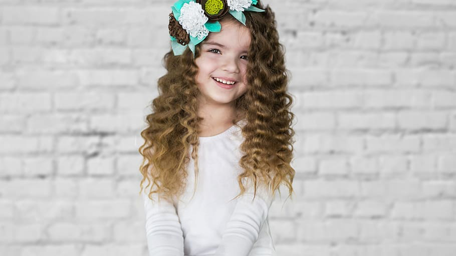 Curly Hair Smiley Little Girl Is Wearing White Dress Sitting In White Brick Wall Wallpaper HD