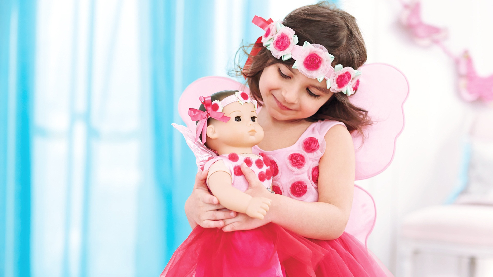 Little Girl With Wings Is Wearing Pink Flowers Dress And Headband Holding Doll With Hands HD