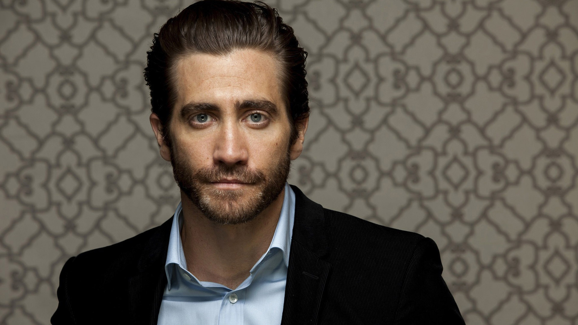 Ash Eyes Jake Gyllenhaal Is Standing In A Print Wall Wallpaper Wearing Black Coat HD
