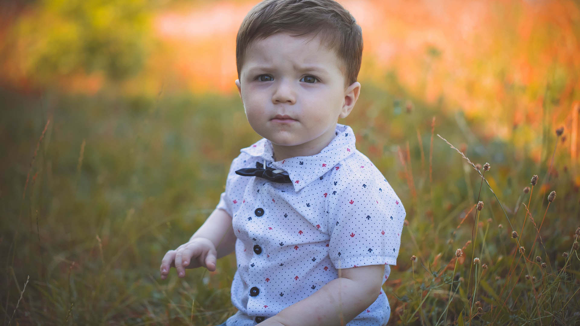 Baby Boy Is Sitting On Grass In Blur Wallpaper Wearing White Dress HD